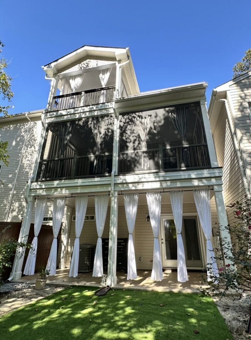 Three-story house with balconies and white curtains